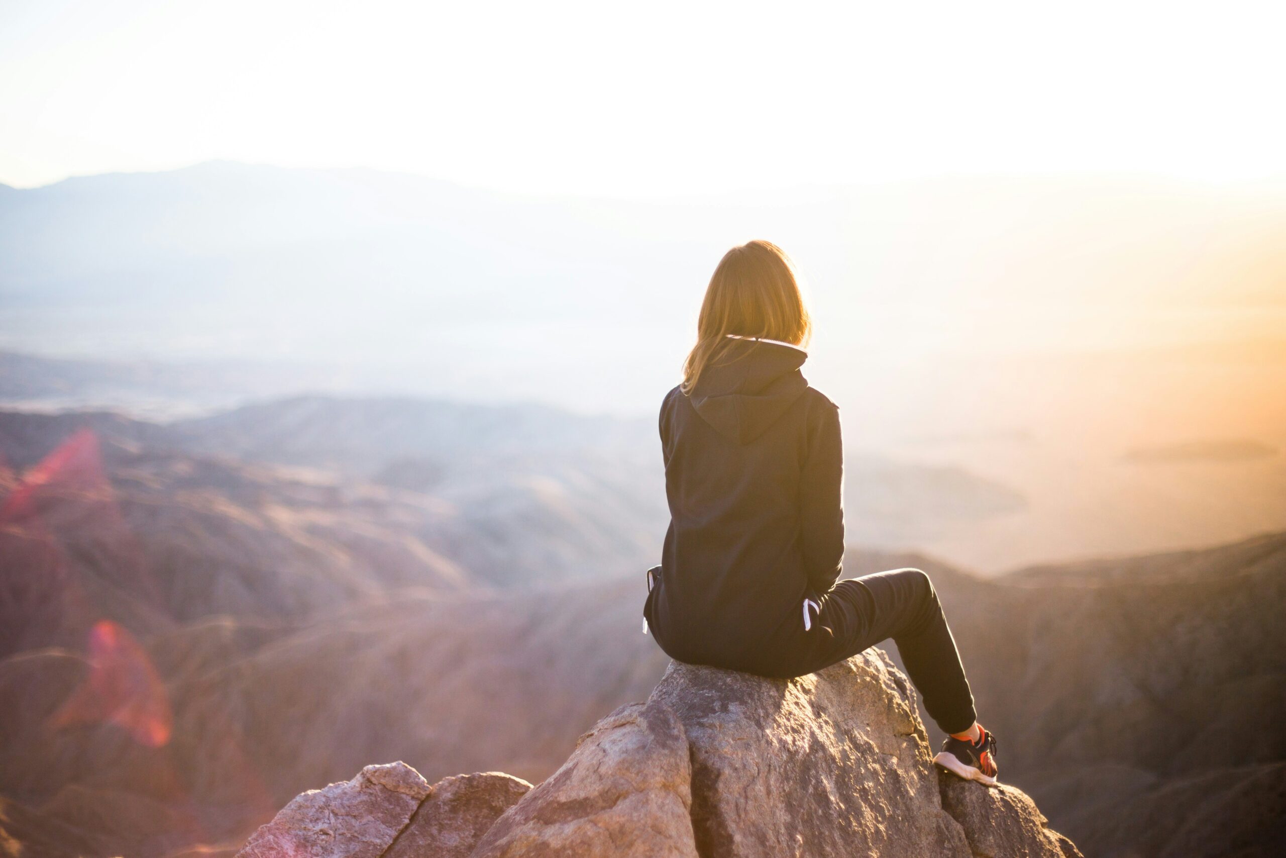 lady sitting on a mountain top getting mental clarity